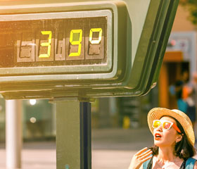 Mujer angustiada en la calle al lado de un termómetro con 39 grados