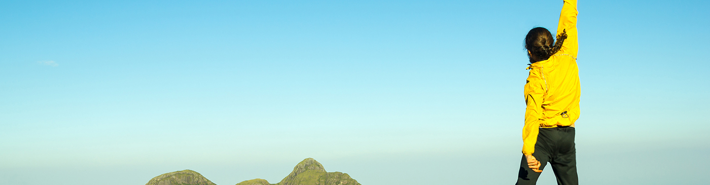 Mujer celebrando la llegada a la cima de una montaña